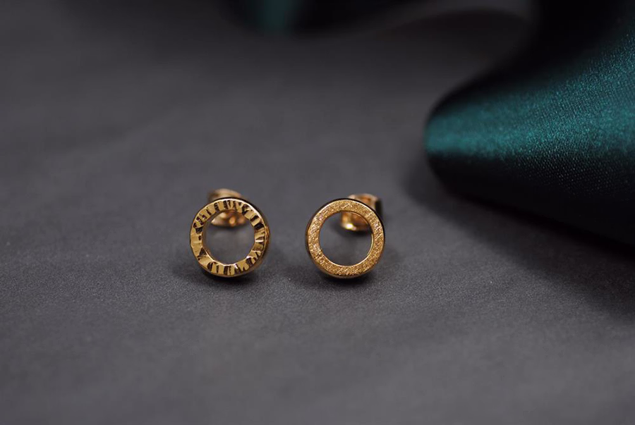 Örhängen tillverkade av en slät guldring. Exempel på ytor som gör ditt smycke personligare.